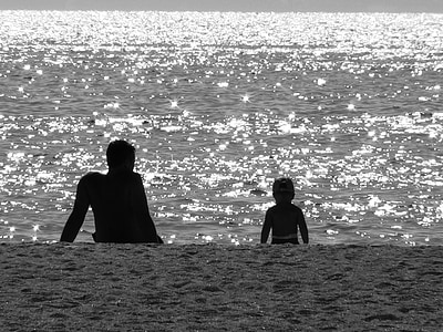 silhouette of man and child facing seashore during daytime thumbnail