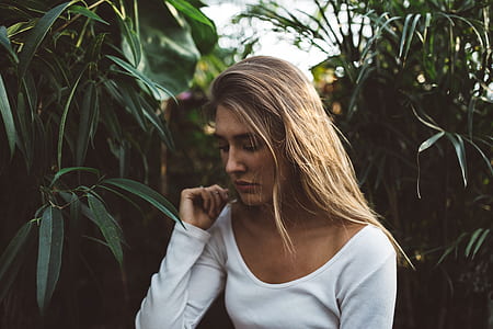 woman in white scoop-neck long-sleeved top near green leaf tree thumbnail