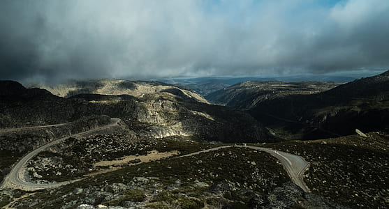 aerial photography of mountains and roads under cloudy sky thumbnail