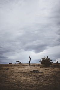 man standing on plain field during daytime thumbnail