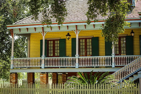 yellow and white wooden house in front of wooden fence thumbnail