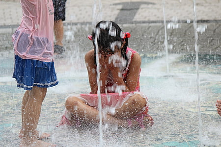 girl playing on outdoor water fountain beside another girl thumbnail