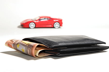 black leather bi-fold wallet with banknotes beside red die-cast toy thumbnail