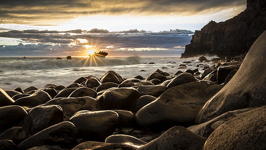 pile of gray stones near sea during sunset thumbnail