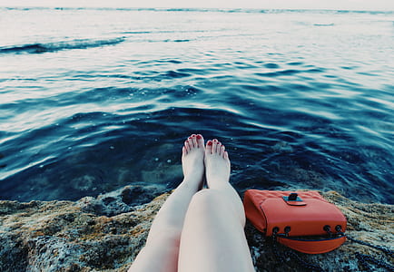 woman sitting beside bag in front of body of water thumbnail