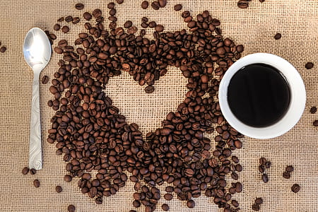 white ceramic teacup with coffee inside beside coffee beans thumbnail