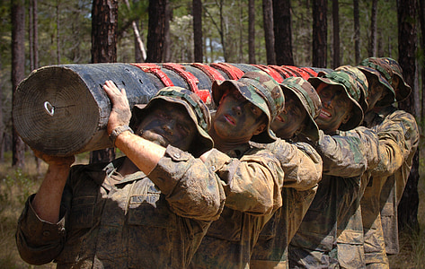 soldiers carrying gray wooden post at daytime thumbnail