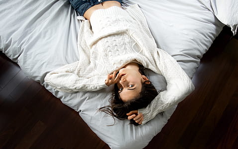 woman lying on white bed while covering her face thumbnail