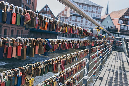 padlocks on railings beside body of water and with houses behind thumbnail