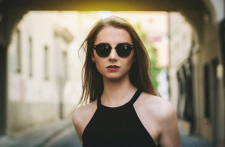 selective focus photography of woman with sunglasses walking on narrow path thumbnail