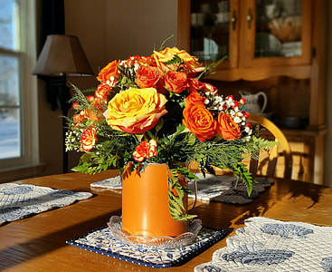 orange and yellow petaled flower in vase on wooden table thumbnail