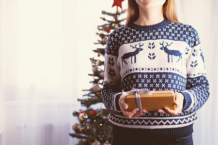 woman wearing blue and white sweater holding gift box thumbnail