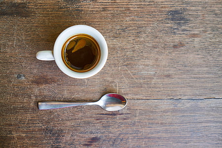 white ceramic teacup and gray spoon on brown wooden surface thumbnail