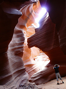 man in blue shirt taking picture inside the canyon during daytime thumbnail