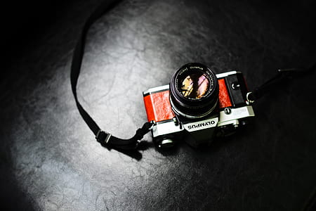 black and silver Olympus DSLR camera on black surface thumbnail