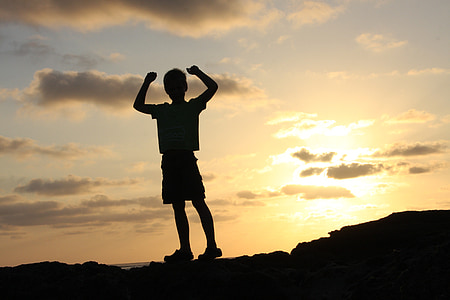 silhouette photo of boy on top of hill during daytime thumbnail