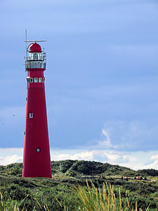 red lighthouse in green grassland under clear blue sky thumbnail
