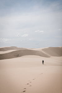 man walks on desert during daytime thumbnail