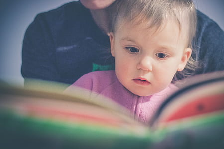 baby in purple shirt reading book thumbnail