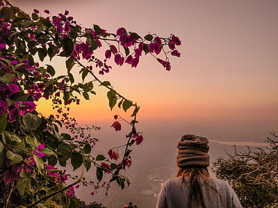 woman wearing brown hat beside pink petaled flowers thumbnail