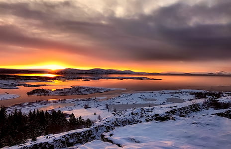 silhouette photo of snow field facing body of water thumbnail