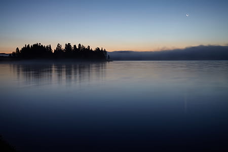 calm body of water beside silhouette of trees during golden hour thumbnail