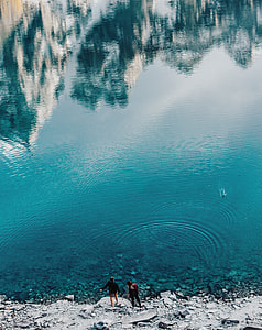 two persons standing near body of water thumbnail