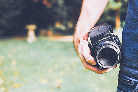 selective focus photography of man holding DSLR camera thumbnail