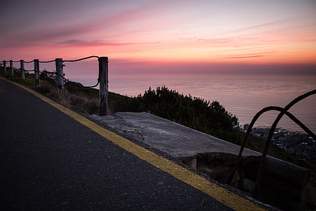 gray asphalt road near sea at golden hour thumbnail