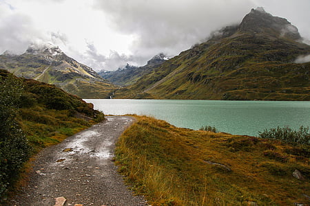 empty road trail beside lake overlooking mountains covered with fog at daytime thumbnail
