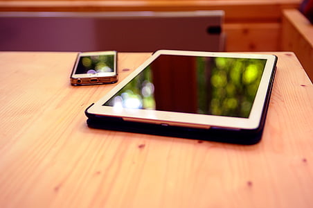 iPad on beige table beside iPhone thumbnail