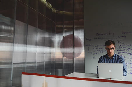 man in blue dress shirt looking at silver MacBook in white room thumbnail