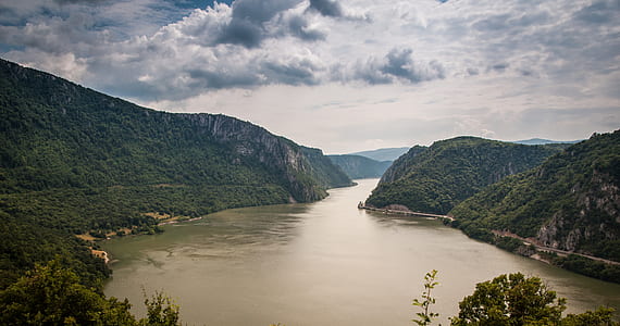 body of water surrounded by mountains covered with green leaf trees thumbnail