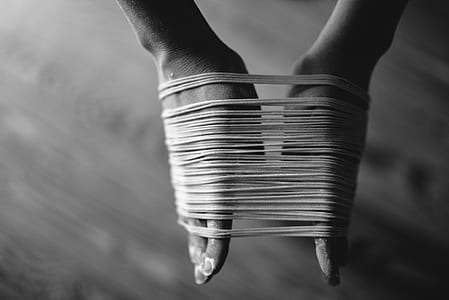 grayscale photo of person's hands binded by threads thumbnail