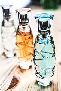 Three Assorted Clear Glass Perfume Spray Bottles on Brown Wooden Surface thumbnail