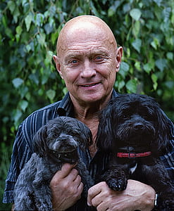 man in black pinstriped shirt carrying puppies thumbnail