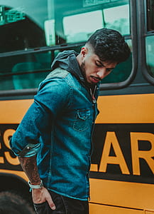 man standing beside yellow bus thumbnail