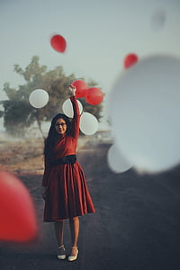 selective focus of woman in red dress holding balloon thumbnail