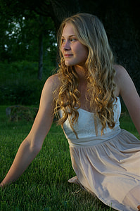 woman wearing white and beige floral dress sitting on green grass field thumbnail