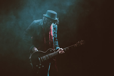 person wearing suit jacket and fedora hat playing guitar thumbnail