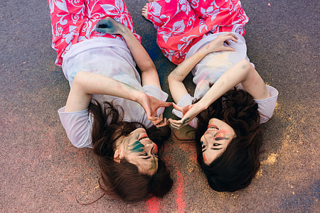 two women laying on floor doing heart sign together thumbnail