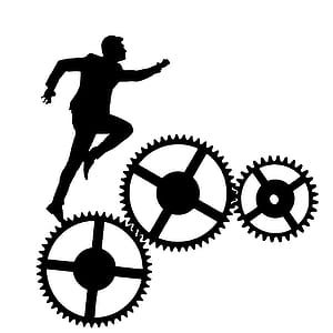 Silhouette of man running over interconnected gears. thumbnail