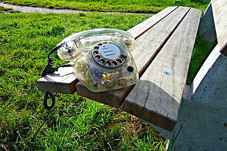 clear rotary phone on wooden bench during daytime thumbnail