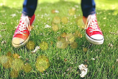 person wearing red low-top sneakers jumping on green grass thumbnail