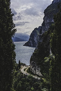 road beside mountain and body of water thumbnail