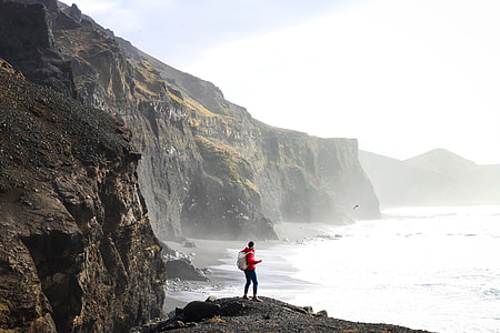 person in mountain near body of water during cloudy sky thumbnail