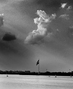 Grayscale Photo of Flag and Clouds thumbnail