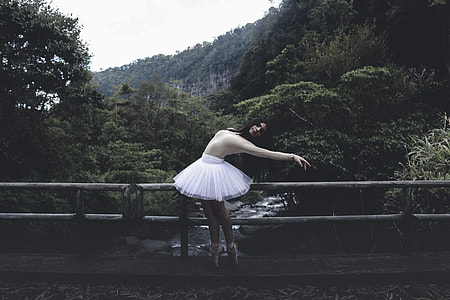ballerina standing on bridge surrounded by trees thumbnail