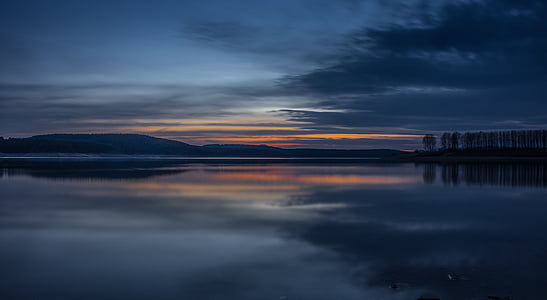 calm body of water near gray clouds during sunset thumbnail