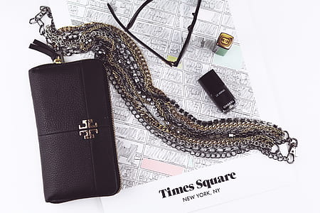 black Tory Burch leather long wallet with gold-and-silver chain necklace on table thumbnail